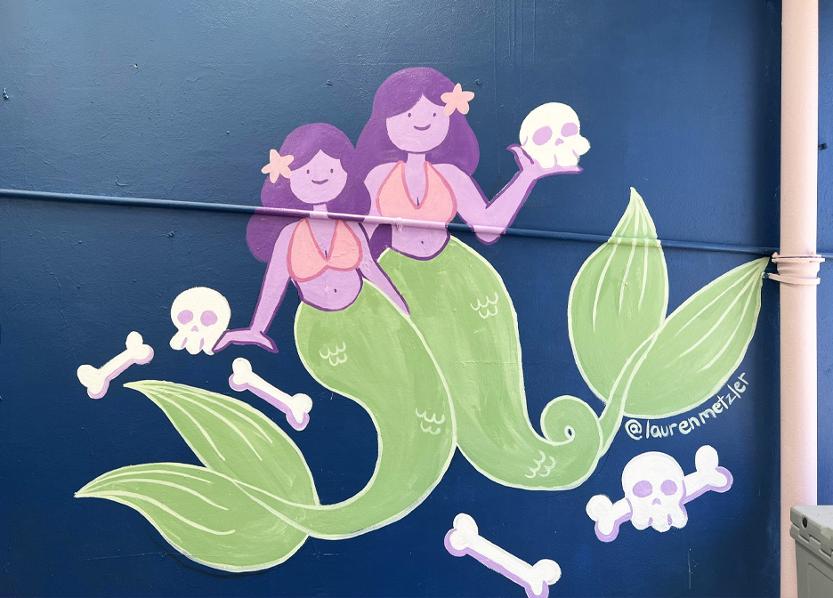 a mural of cartoon siren mermaids with skulls and bright colours