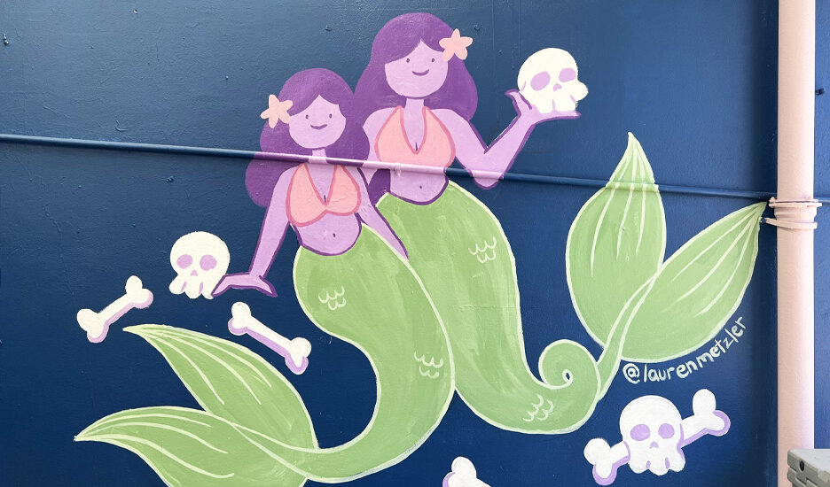 a mural of cartoon siren mermaids with skulls and bright colours